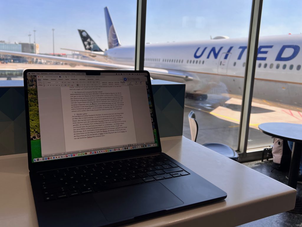 Ein Laptop am Flughafen. Jemand arbeitet am Flughafen an seinem Laptop, während er auf den Flug wartet. Ablenkungen lauern an jeder Ecke – aber sogar unterwegs ist Deep Work möglich. Ich empfehle dafür Noise-Cancelling-Kopfhörer und einen Wecker – damit du deinen Flug nicht verpasst.