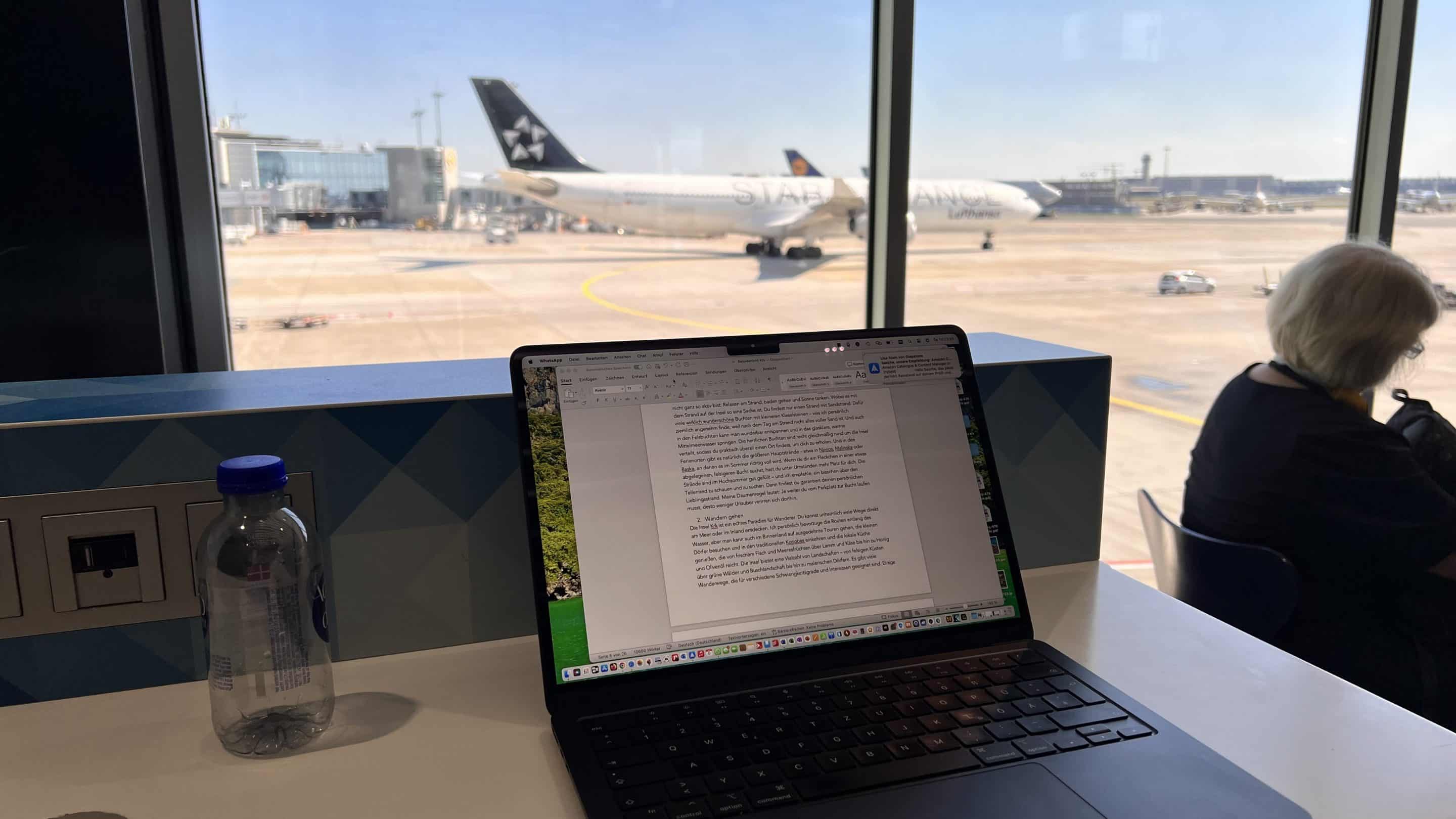 Laptop mit Textentwurf am Flughafen vor einem Flugzeug