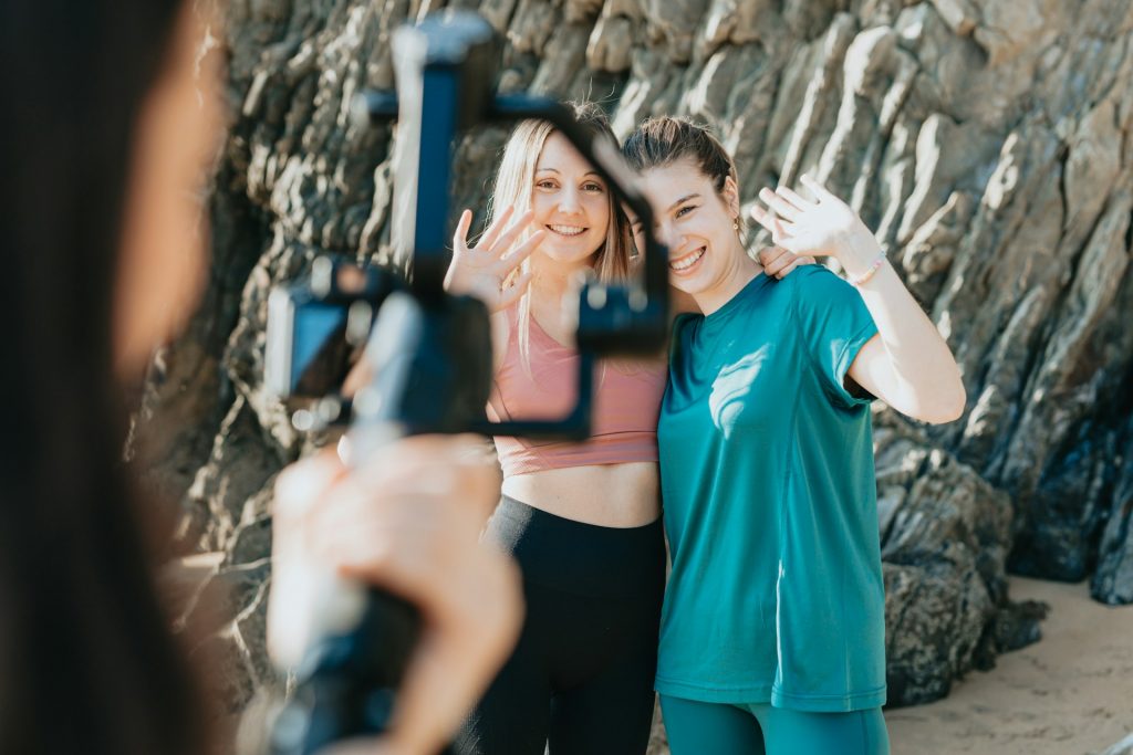 Drei Frauen produzieren mit einer Kamera ein Video, das sie mutmaßlich auf Social Media posten wollen. Zwei von ihnen stehen vor der Kamera, eine Frau steht hinter der Kamera. Im Hintergrund sieht man eine Outdoor-Landschaft. Mit dem Klarheits-Kompass kannst du herausragende Content-Pläne für Blogs, Social-Media-Beiträge und Videoscripts machen.