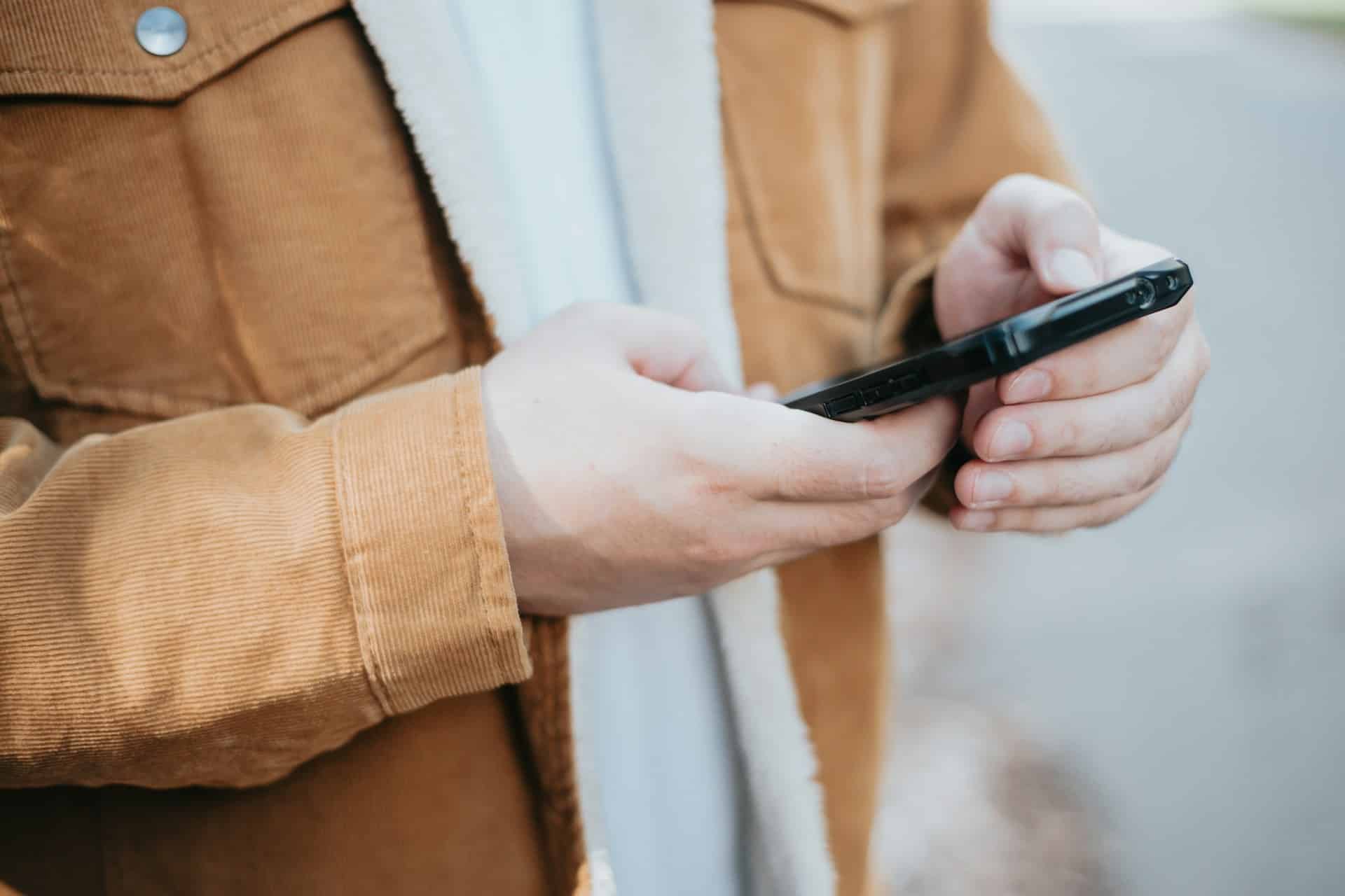 Hände bedienen ein Smartphone – Symbolbild für mobile Spracheingabe und KI-Arbeit
