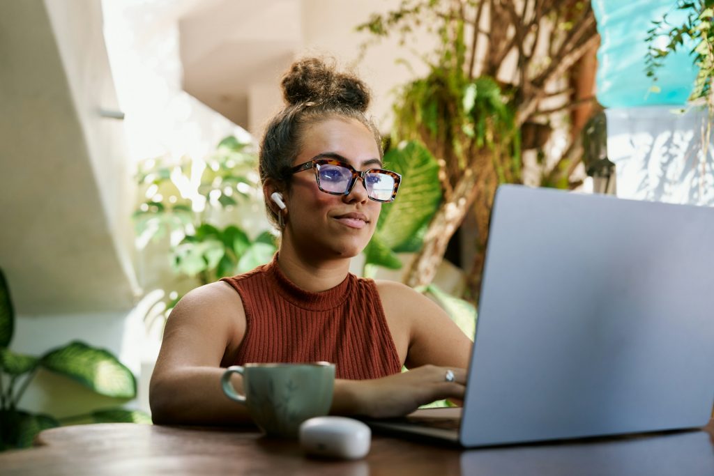 Die Zusammenarbeit mit KI und somit deine KI-Strategie lässt sich auf eine simple Gleichung reduzieren: Deine Expertise + die Fähigkeiten der KI > Deine Expertise allein > Die KI allein
Eine Frau sitzt vor einem Laptop und hat Kopfhörer in den Ohren. Sie trägt eine Brille und schaut auf den Bildschirm.