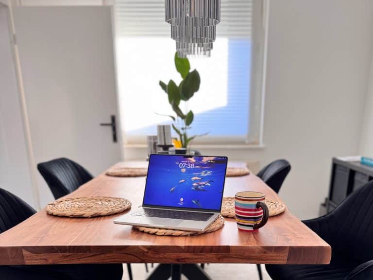 MacBook und iPhone auf einem Esstisch als persönlicher Arbeitsplatz für KI-gestützte Content-Arbeit.