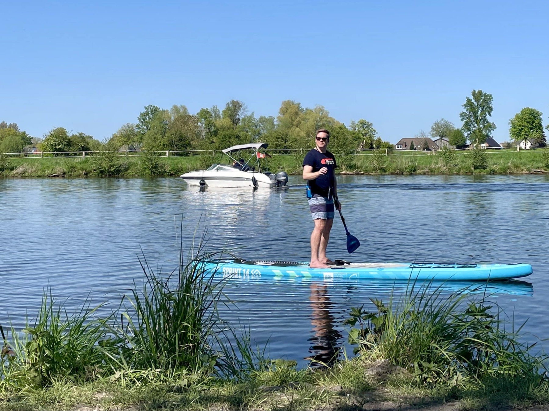 Sascha Tegtmeyer steht mit Paddel auf einem SUP-Board auf ruhigem Wasser