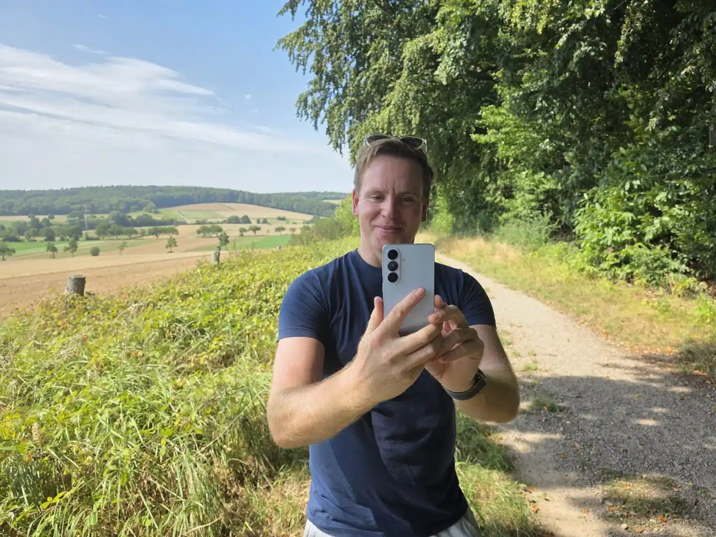 Sascha Tegtmeyer hält das hellblaue Samsung Galaxy S26 auf einem Feldweg