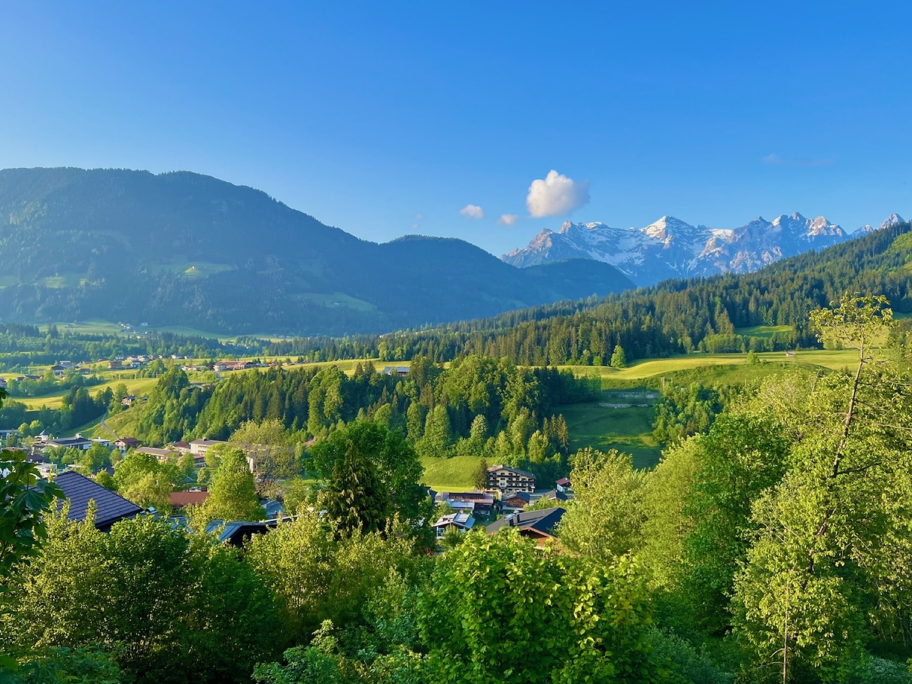 Blick über Fieberbrunn auf grüne Berge und schneebedeckte Gipfel