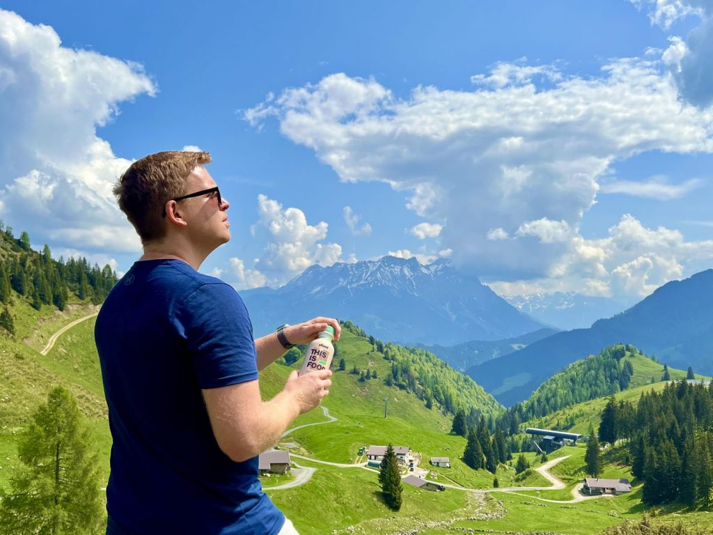 Sascha hält eine yfood-Flasche vor dem Bergpanorama in Fieberbrunn