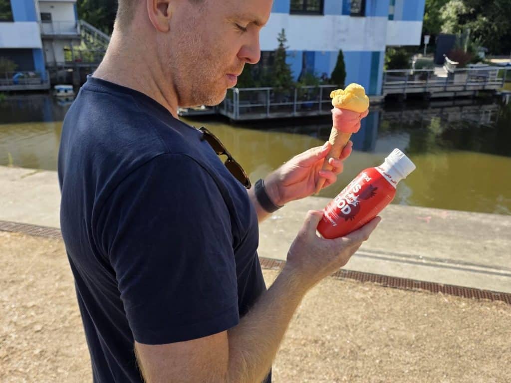 Sascha hält eine yfood Fruity Strawberry Flasche neben einer Eiswaffel
